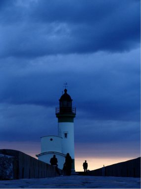TREPORT Deniz feneri, dikey renkli dijital fotoğraf: Normandiya, Seine Denizcilik, bulutlu bir gökyüzü altında, iskelenin sonundaki Treport deniz feneri, bir adam sırtı ona doğru yürürken, üç figür ayağının altında.