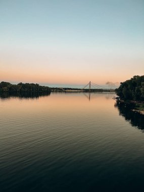 Akşamları güneşin altında ağaçlarla çevrili güzel bir göl görüntüsü.