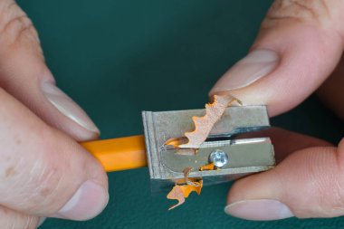 Bir insanın ellerinin kalemini keskinleştirdiği yakın plan.