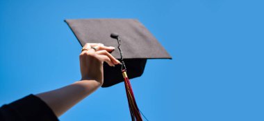 Mavi gökyüzüne mezuniyet şapkası takan yüksek lisans öğrencisi.