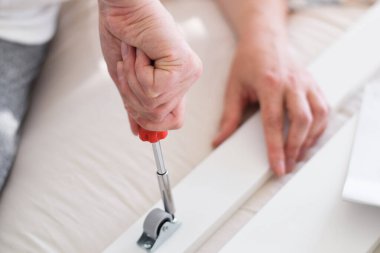 Mobilya montajı için tornavida kullanan kadınların elleri kapalı.