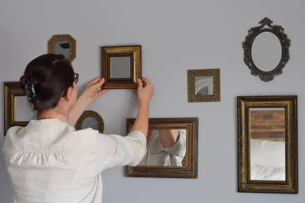 Kadın galeri duvarının bir parçası olarak bir ayna asıyor.