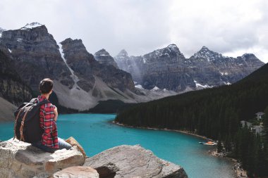 Sırt çantalı kadın Banff 'taki Moraine Gölü manzarasının tadını çıkarıyor.