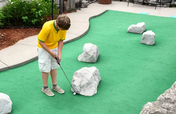 Genç adam çimenlikte mini golf oynuyor