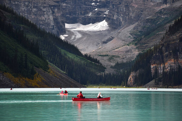 People riding in canoes on lake Louise surrounded by mountains