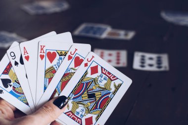 Kadınların el ele tutuşup masada kağıt oynamaları.