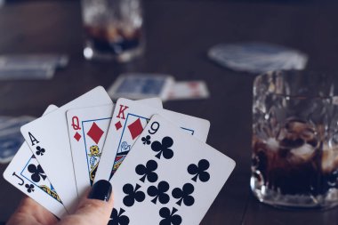 Kadınların el ele tutuşup masada içki bardağıyla kağıt oynamaları.