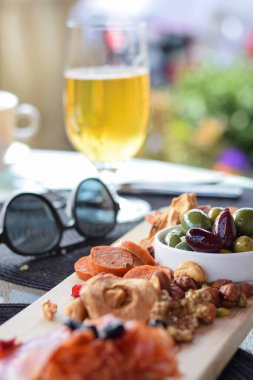 Restoran teras masasında kurutulmuş et, kurutulmuş meyve ve zeytinli şarküteri tahtası. 