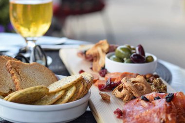 Restoran verandasında kurutulmuş et, kurutulmuş meyve, zeytin ve kraker ile şarküteri tahtası.