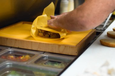 Restoran çalışanı sipariş vermek için sandviç paketliyor.