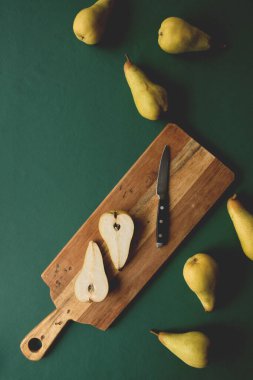 Koyu yeşil arka planda kesme tahtasındaki armutların üst görünümü