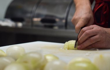 Restoran çalışanı soğanları bıçakla doğruyor.