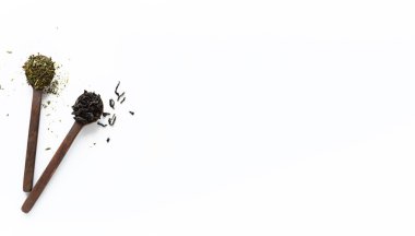 Beyaz arka planda izole edilmiş tahta kaşıklardaki siyah ve yeşil yaprak çayları, kopya dalgasıyla üst manzara