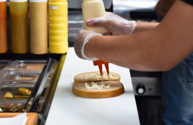 Mutfak çalışanı, yemek siparişi için sandviç hazırlıyor.