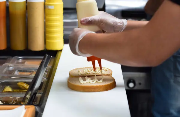 Mutfak çalışanı, yemek siparişi için sandviç hazırlıyor.