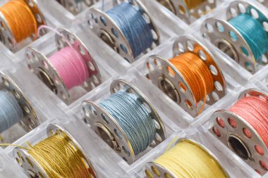 Macro closeup colorful sewing thread bobbins organized in tray clipart