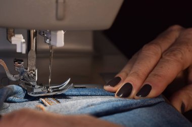 Terzi kadın kotları dikmek için dikiş makinesi kullanıyor.