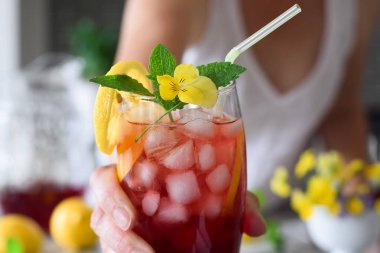 Yakından bir kadın eli, renkli, kırmızı, soğuk bir yaz içeceğiyle uzanıyor.