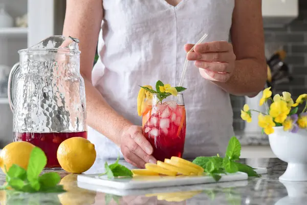 Kadın renkli kırmızı soğuk yaz içeceğine pipet koyuyor. 