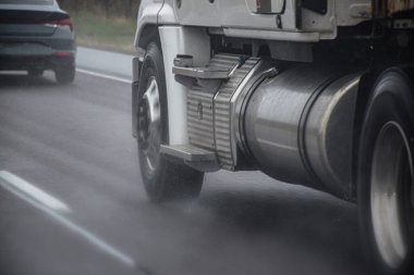 Traktör römorku yağmurda yüksek hızda gidiyor.