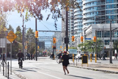 Toronto, Ontario, Kanada - 17 Ekim 2021: Queens Quay limanında bisiklet yolunda koşan ve bisiklet süren insanlar