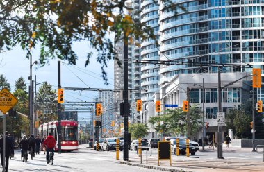 Toronto, Ontario, Kanada - 17 Ekim 2021: TTC tramvayı, Queens Quay şehir merkezinde insanlar bisiklet ve trafik