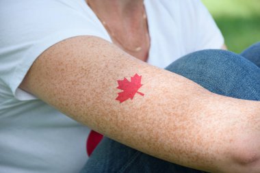 Kanada Günü 'nde kadınların kolunda kırmızı akçaağaç yaprağı dövmesi.