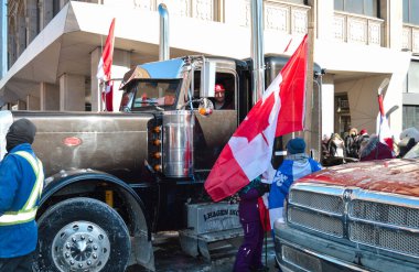 Ottawa, Ontario, Canada - February 5, 2022: Trucker sitting in truck cabin smiling talking to protestor at Freedom Convoy protest against pandemic restrictions and mandates clipart