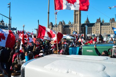 Ottawa, Ontario, Canada - February 5, 2022: Crowd of protesters in front of Parliament Hill building at Freedom Convoy protest against pandemic restrictions and mandates clipart