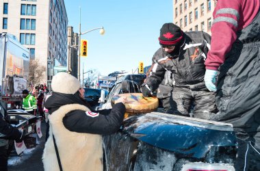 Ottawa, Ontario, Canada - February 5, 2022: Trucker signing traditional indigenous drum for woman at Freedom Convoy protest against pandemic restrictions and mandates clipart