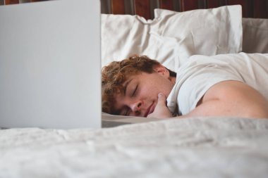 Genç adam dizüstü bilgisayarın önünde uyuyakaldı.