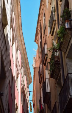 Dar Barcelona Caddesi 'ndeki iki apartmanın arasındaki mavi gökyüzüne bakıyorum.