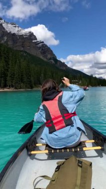 Alberta Kanada 'daki Banff Ulusal Parkı' nda Moraine Gölü 'nde kanoda kürek çeken genç bir kız.