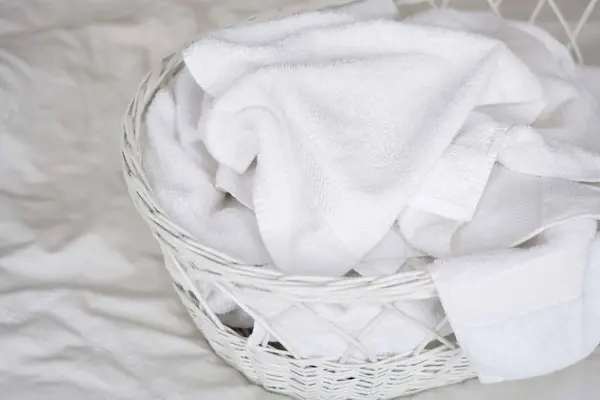 Yatağın üstündeki sepette beyaz havlu yığını.