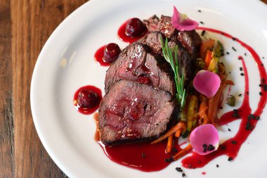 Biberiye filizi ile süslenmiş, jülyen sebze ve kiraz sosuyla servis edilen dilimlenmiş dana eti.