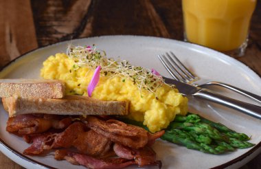 Çırpılmış yumurta, pastırma, haşlanmış kuşkonmaz ve kızarmış ekmek ile kahvaltı tabağı.