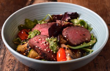 Sıcak dilimlenmiş biftek ve ızgara sebze salatasıyla kase.