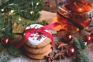 Süslemelerle çevrili kırmızı fiyonklu Noel kurabiyeleri yığınının yakın görüntüsü