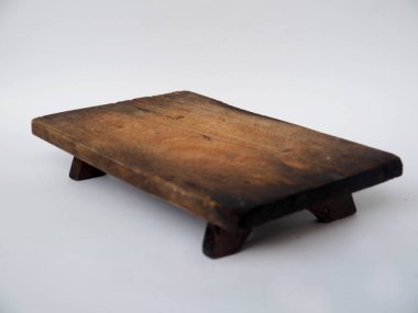 Beyaz bir yüzeye yerleştirilmiş, aşçılık ve dekoratif amaçlar için ideal, eski dokusunu ve minimalist tarzını sergileyen bir tahta kesme tahtası. Kırsal mutfaklar için mükemmel ya da klasik odaklı