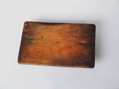 Beyaz bir yüzeye yerleştirilmiş, aşçılık ve dekoratif amaçlar için ideal, eski dokusunu ve minimalist tarzını sergileyen bir tahta kesme tahtası. Kırsal mutfaklar için mükemmel ya da klasik odaklı