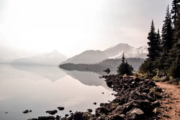 Kanada, British Columbia 'daki Garibaldi Gölü, karlı dağları ve sık yeşil ormanları yansıtan ayna benzeri sulara sahiptir. Engebeli kayalık bir kıyı şeridi tarafından çerçevelenmiş el değmemiş bir dağlık arazi boyunca.