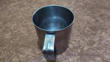 Kahverengi bir tabanda kahve ya da çay için boş bir alüminyum bardak, yakın plan..