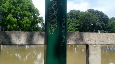 Grafiti çizgileri olan kasvetli yeşil renkli bir bahçede sokak lambası manzarası. Arkaplanda parlak bir gökyüzü.