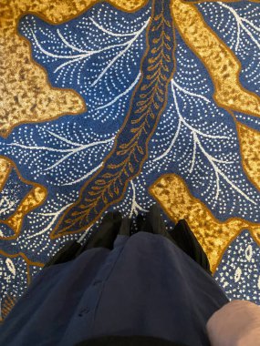 Siyah etekli, mavi ve sarı yapraklı halıda duran kadın elbisesi.. 