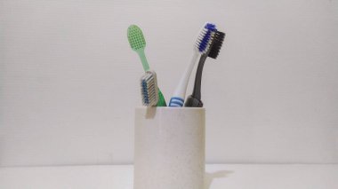 Beyaz arka planda beyaz bardaktaki çok renkli diş fırçalarının yakın plan çekimi, diş konsepti.