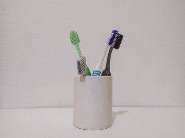 Beyaz arka planda beyaz bardaktaki çok renkli diş fırçalarının yakın plan çekimi, diş konsepti.