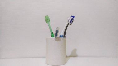 Beyaz arka planda beyaz bardaktaki çok renkli diş fırçalarının yakın plan çekimi, diş konsepti.