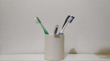 Beyaz arka plandaki beyaz bardaktaki diş fırçasını almak, diş konsepti.