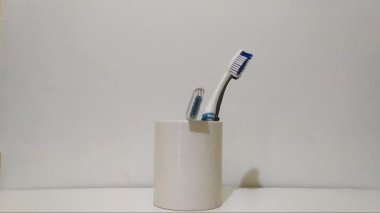 Diş fırçasını beyaz arka plan üzerine beyaz bardağa koymak, diş konsepti.