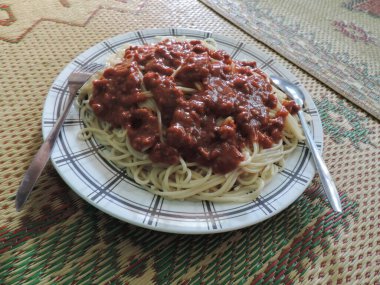 Baharatlı biberli spagetti, plastik tabakta servis edilir..